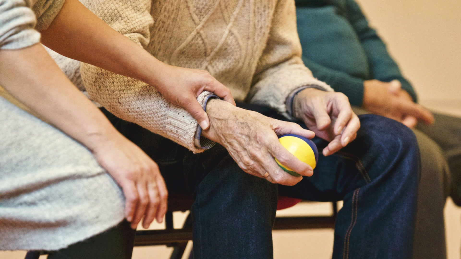 Caregiver grasps wrist of elderly man, statistically a victim of elder abuse.