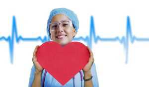 Smiling nurse holding a red paper cut our in the shape of a heart for heart disease, the number one killer of women. 