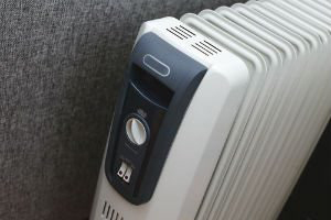 A radiant space heater with a blue control panel against a gray wall.