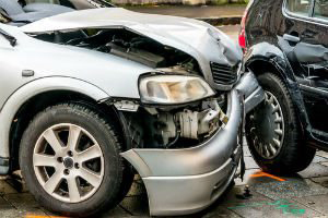 Damage to front of a silver sedan car after an accident.