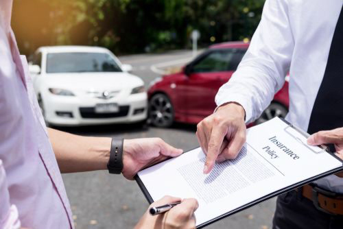 man signing insurance claim form held by insurance adjuster