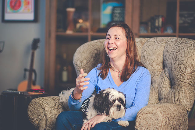 Hillary Coltharp sitting on a couch with a puppy in her lap.