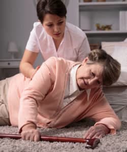 nurse helping elderly resident get up from a fall